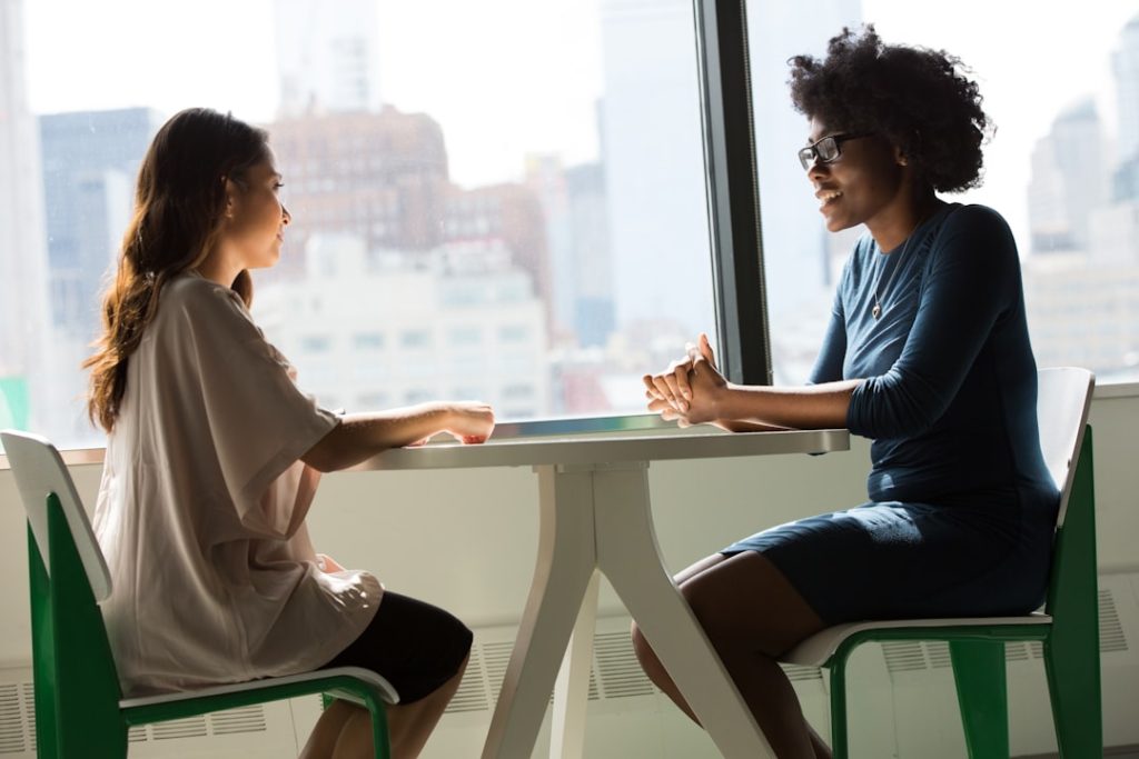 Life coach in conversation with a client across a table, discussing goals between sessions