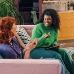 A wellness coach and client sitting together in a relaxed one-on-one coaching conversation.