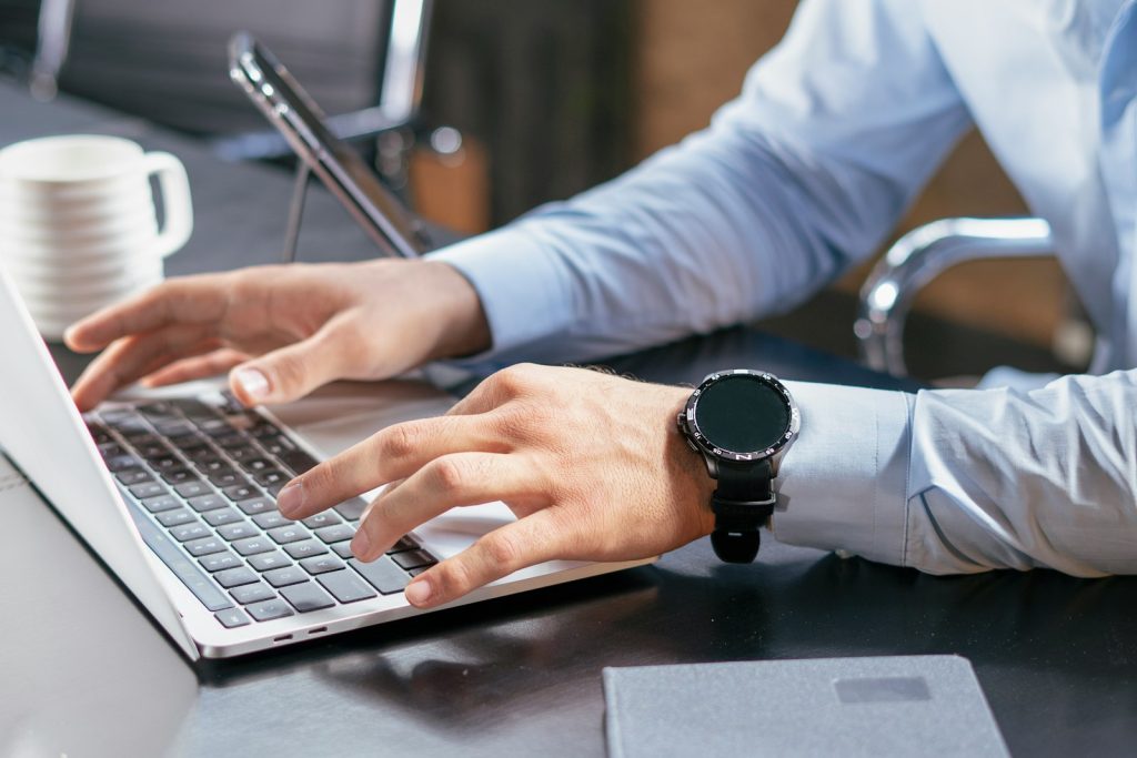 A coach working at a laptop workspace reviewing coaching software