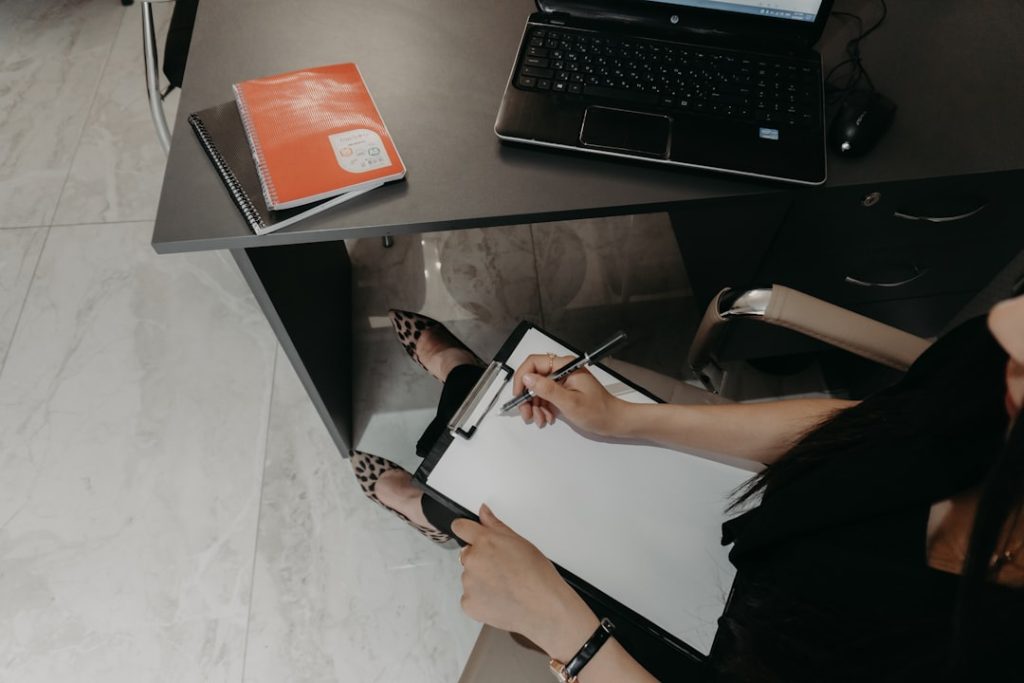 Organizing client notes on a clipboard beside a laptop.