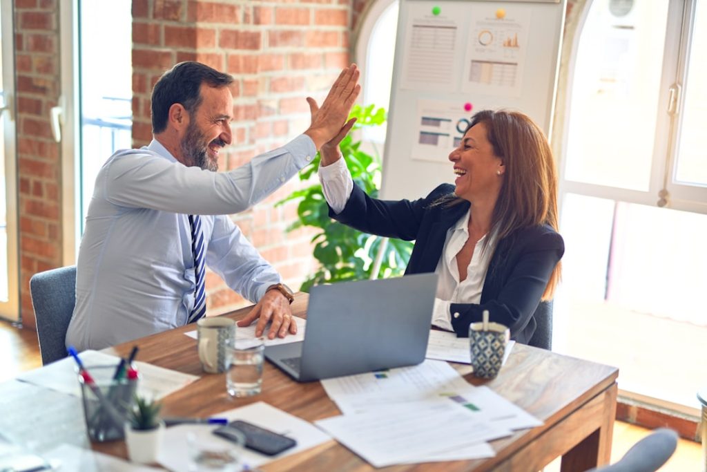 Two professionals celebrating growth at a desk.