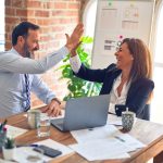 Two professionals celebrating growth at a desk.