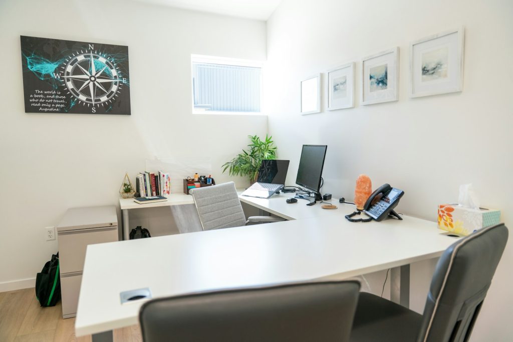An organized coaching practice workspace with dual monitors and a compass print, the kind of clean setup coaches leaving Notion want to reach