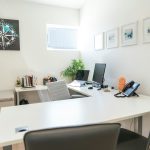An organized coaching practice workspace with dual monitors and a compass print, the kind of clean setup coaches leaving Notion want to reach