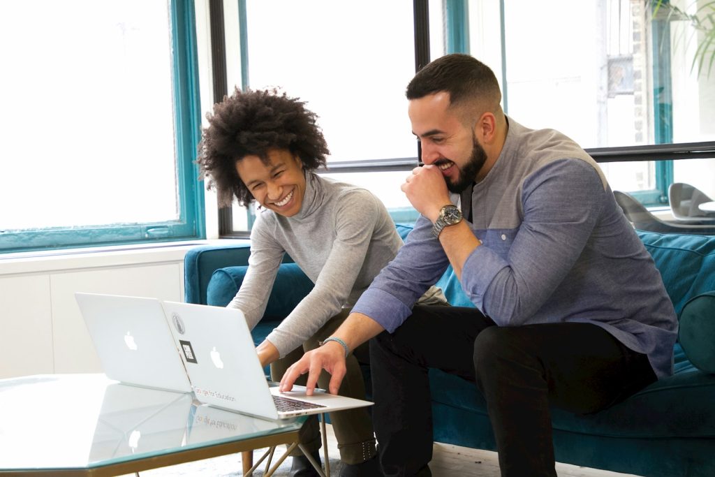 Two people comparing coaching software options together on a laptop