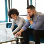 Two people comparing coaching software options together on a laptop