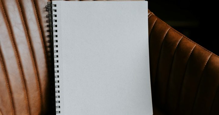A blank spiral-bound notebook resting upright on a brown leather armchair