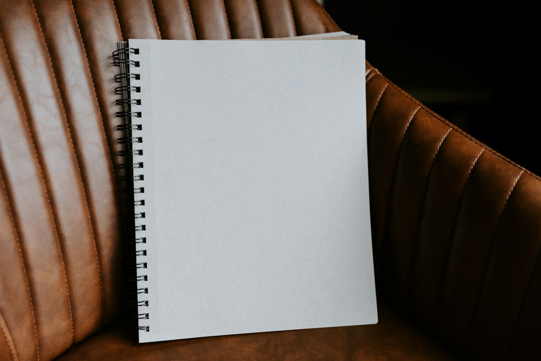 A blank spiral-bound notebook resting upright on a brown leather armchair